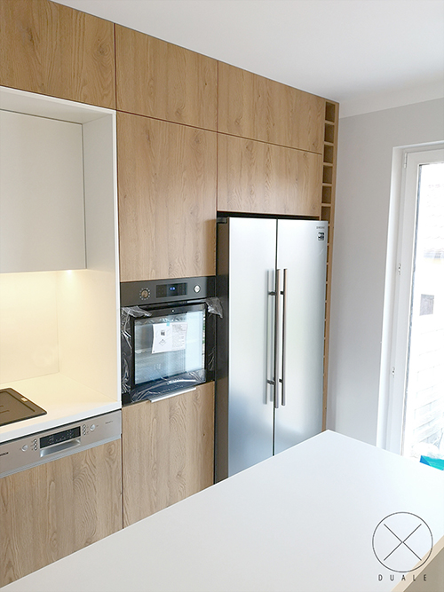 Kuchnia z dużą lodówką i regałem obok
